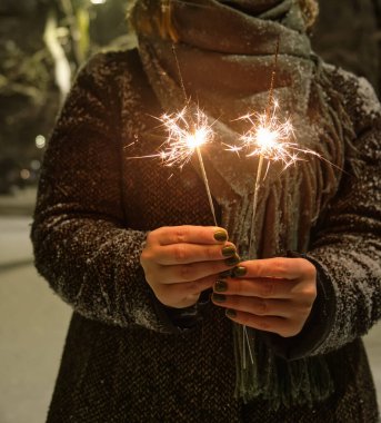 Gece lambalarının arka planında maytap olan bir el. Gece lambalarının arka planında maytap olan şehrin neşeli ışıklandırması..