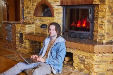 Genç ve mutlu bir adam şöminenin başında oturuyor. 