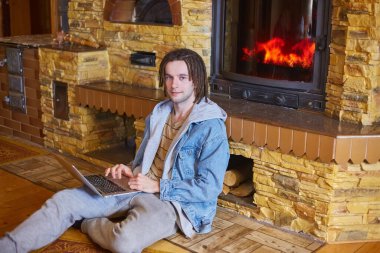 Genç ve mutlu bir adam şöminenin başında oturuyor. 