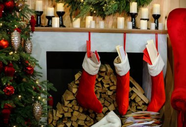Yılbaşı odasındaki şöminede mumlar, Noel çam dalları Noel çorapları, Noel ağacı ve Noel şöminesi.