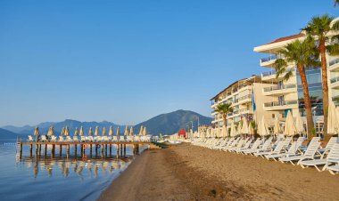 İnsansız kumsal ve güneş pansiyonları, şemsiyeler, palmiye ağaçları, Marmaris, Türkiye,
