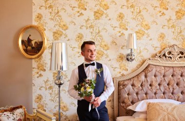 Pahalı bir iç mekanda düğün sabahı damadı. Düğününde mutlu damat. Damat evde giyinmiş. Moda. Düğünden önce damat hazırlığı.