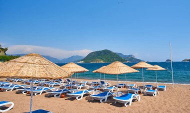 İnsansız kumsal ve güneş pansiyonları, şemsiyeler, palmiye ağaçları, Marmaris, Türkiye,