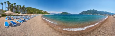İnsansız kumsal manzarası ve güneş panoları, şemsiyeler, palmiye ağaçları, Marmaris, Türkiye,