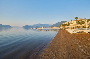 Sabahın köründe ıssız bir plaj. Şafakta kumsalda. Boş güneşlik. İnsansız plaj. Marmaris, Türkiye.
