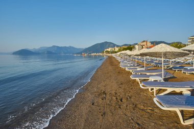 İnsansız kumsal ve güneş pansiyonları, şemsiyeler, palmiye ağaçları, Marmaris, Türkiye,