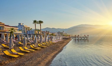 Sabahın köründe ıssız bir plaj. Şafakta kumsalda. Boş güneşlik. İnsansız plaj. Marmaris, Türkiye.