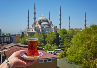 Türkiye 'nin İstanbul kentindeki Sultanahmet Camii olarak da bilinen Mavi Cami' nin önünde geleneksel Türk çayıyla el ele tutuşan bir kadın. İstanbul 'un başlıca eğlenceleri.