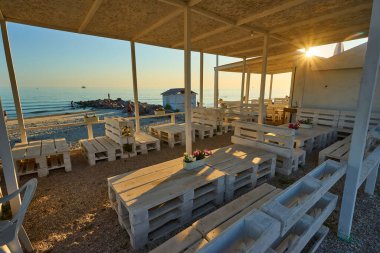 Yaz tatili için cennet gibi bir tropik tatil beldesindeki kumsalda Thatched plaj şemsiyeleri ve şezlongları