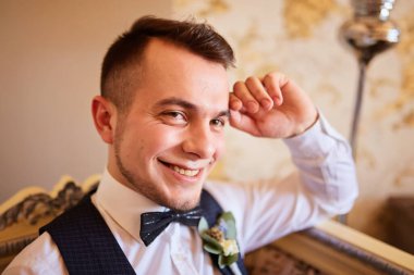 Pahalı bir iç mekanda düğün sabahı damadı. Düğününde mutlu damat. Damat evde giyinmiş. Moda. Düğünden önce damat hazırlığı.