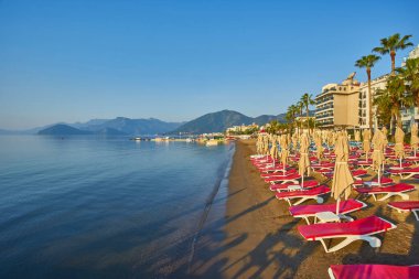 İnsansız kumsal ve güneş pansiyonları, şemsiyeler, palmiye ağaçları, Marmaris, Türkiye,