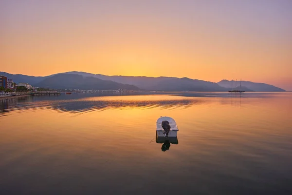 穏やかな海での日の出を反映した山と孤独なモーターボートトルコのマーマリス — ストック写真