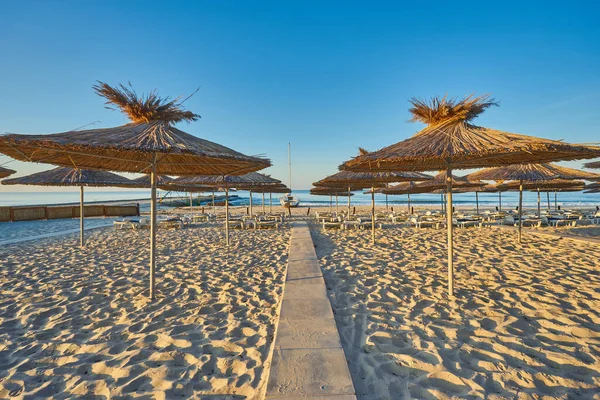 海滩上的黎明太阳椅和遮阳伞在升起的阳光下 没有人的海滩 — 图库照片