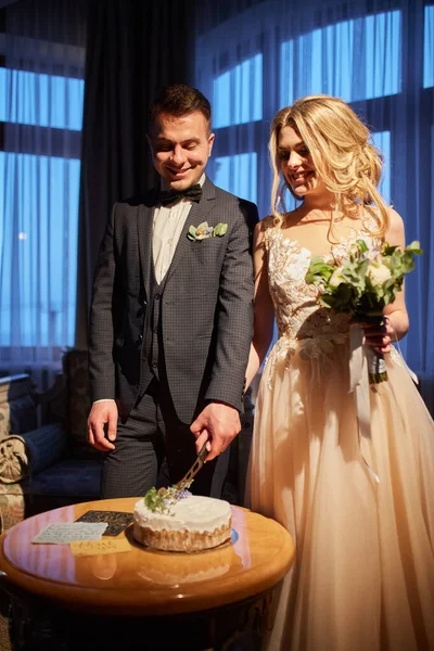 一对年轻夫妇坐在婚礼的桌旁 切蛋糕 — 图库照片