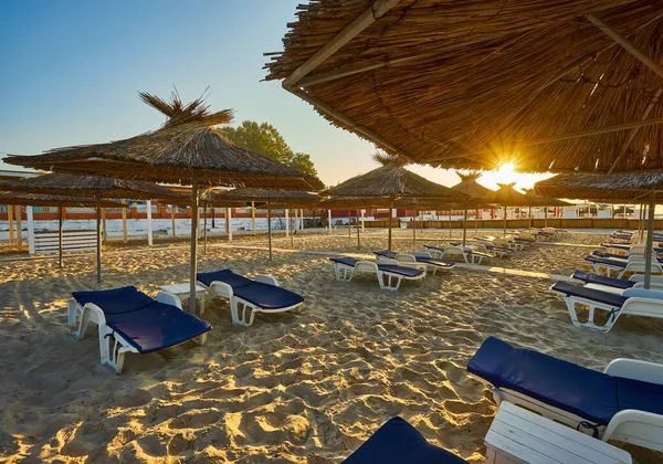 海滩上的黎明太阳椅和遮阳伞在升起的阳光下 没有人的海滩 — 图库照片