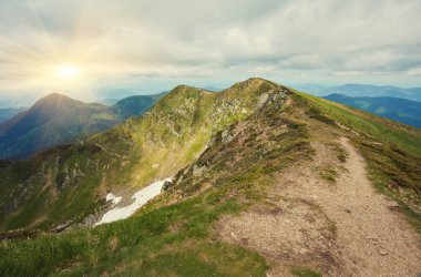 Alpler 'deki güzel cennet manzarası geleneksel dağ evi ve baharda mavi gökyüzünün açtığı güneşli bir günde çiçek açan taze yeşil çayırlar.