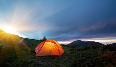 Ayın altında aydınlatılmış turuncu kamp çadırı