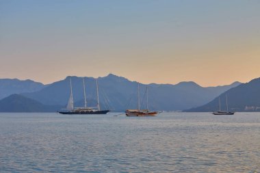 dağ ve yalnız motorlu tekne, sakin bir deniz olan Marmaris 'te gün doğumunu yansıttı, Türkiye