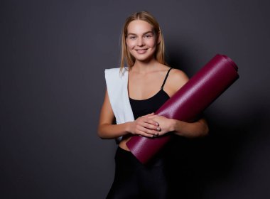 Salonunda egzersiz sonra bekletin. Oturma ve yoga ya da fitness sonra rahatlatıcı bir yoga mat ile spor spor güzel gülümseyen kadın.