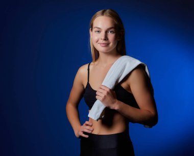 Spor salonunda havlusu olan sarışın genç bir kız. Yakın plan fotoğraf. kopyalama alanı. koyu arkaplan