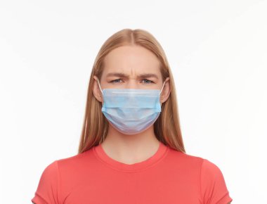 Ciddi genç kadın portresi beyaz stüdyo arka planında koruyucu bir tıbbi maske takıyor, kız üzgün gözler, sağlık ve karantina önlemleri kavramı