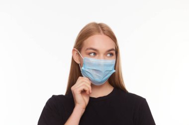 Sarışın, tıbbi maske takan genç bir kadın elleriyle düzeltiyor izole edilmiş beyaz arka planı.