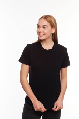 Genç, güzel sarışın kadın, boş siyah tişörtle poz veriyor. Tasarımınız ya da çiziminiz için hazır.