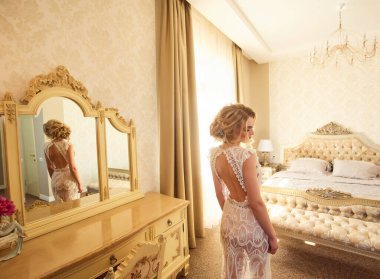 Genç ve güzel bir gelinin şehvetli sabah hazırlığı. Düğün için. Gelinin harcı evin iç kısımlarında. Peignoir 'deki seksi hassas gelin. Lüks saçlı ve makyajlı gelin..