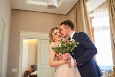 Güzel bir çift gelin ve damat şık iç mekanlarda sarmaş dolaş.