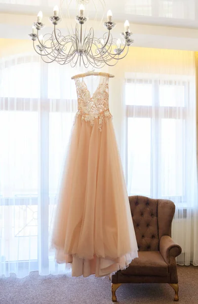 Stock image Luxury wedding dress hanging on the chandelier in a hotel room. Bridal gown. Bridesmaids. Wedding