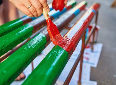 Elindeki fırçayla parlak renklerde bir bank boyuyor, sokağa bir bahçe bankı çiziyor.
