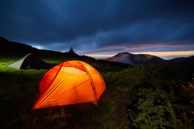 Ayın altında aydınlatılmış turuncu kamp çadırı