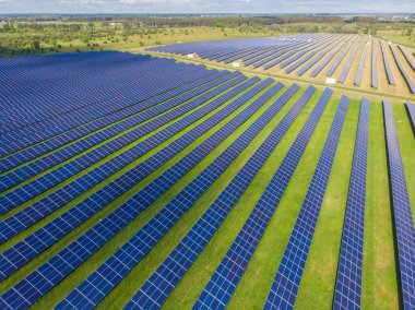 Yeşil çimenlikteki güneş panellerinin havadan görünüşü. İHA atışı, kuş gözü.