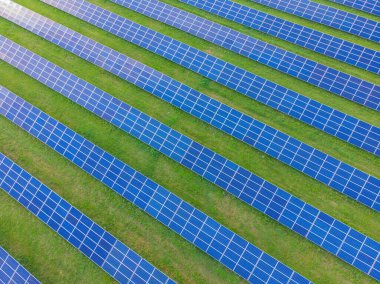Fotovoltaik güneş sisteminin insansız hava görüntüsü. Metalik mavi güneş panelleri, yenilenebilir ve sürdürülebilir enerji teknolojisi. Alternatif enerji, yeşil arkaplana geç.