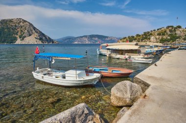 Türkiye 'nin Mugla, Turunc kentindeki tepenin tepesinde Ege Denizi' ndeki mavi lagün, arka planda plaj ve Türk bayrağı bulunan küçük tekneler.