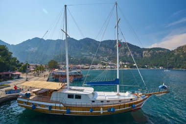 Türkiye 'nin Mugla, Turunc kentindeki tepenin tepesinde Ege Denizi' ndeki mavi lagün, arka planda plaj ve Türk bayrağı bulunan küçük tekneler.