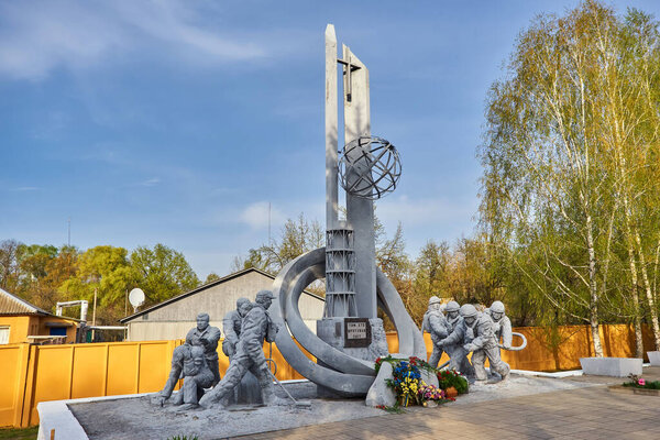 Украина, Чернобыль, 25 апреля 2019 года:. Памятник ликвидаторам аварии на Чернобыльской АЭС. Пожарный в защитном шлеме с пожарным шлангом
