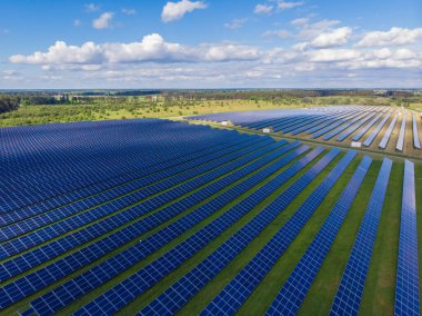 Yeşil çimenlikteki güneş panellerinin havadan görünüşü. İHA atışı, kuş gözü.