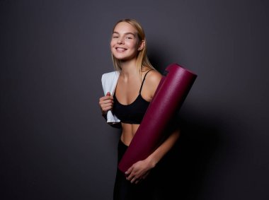 Salonunda egzersiz sonra bekletin. Oturma ve yoga ya da fitness sonra rahatlatıcı bir yoga mat ile spor spor güzel gülümseyen kadın.