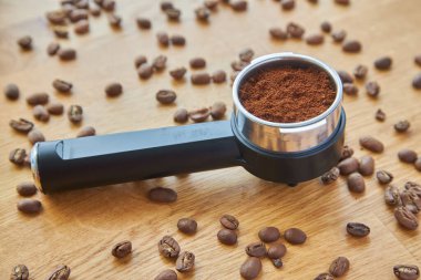 Kahve makinesi boynuzu, içinde kahve var, kahve çekirdeklerinin arka planında.