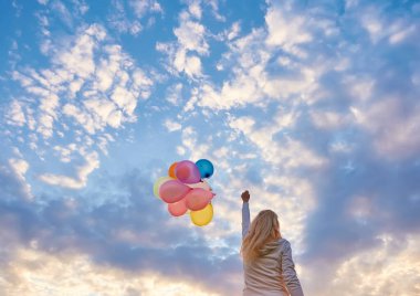 Gün batımında güneşe doğru koşan balonlu bir kız..
