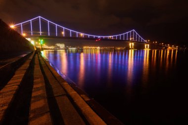 Gece şehri manzarası çok az. Dinyeper nehri üzerindeki yaya köprüsü, Kyiv, Ukrayna
