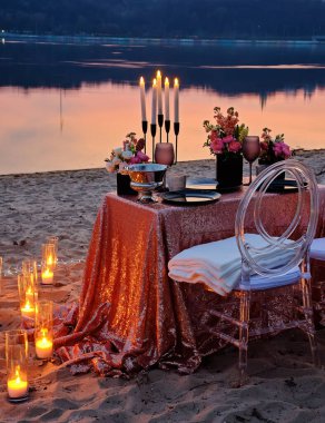 Nehir kıyısında bir randevu, süslü bir masa aşık bir çifti bekliyor. Arka planda şehir ışıkları, akşam Kyiv, Ukrayna.