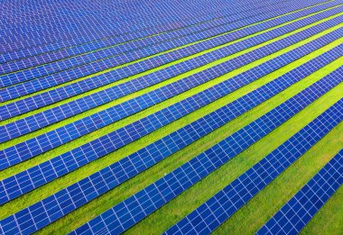 Fotovoltaik güneş sisteminin insansız hava görüntüsü. Metalik mavi güneş panelleri, yenilenebilir ve sürdürülebilir enerji teknolojisi. Alternatif enerji, yeşil arkaplana geç.
