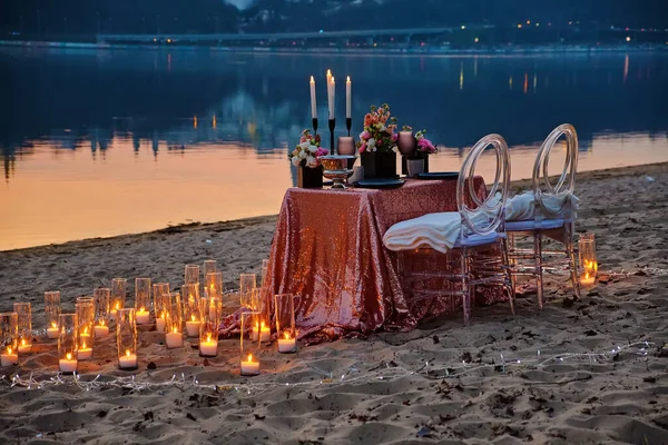 A date on the river bank, a decorated table is waiting for a couple in love. City lights in the background, evening Kyiv, Ukraine.