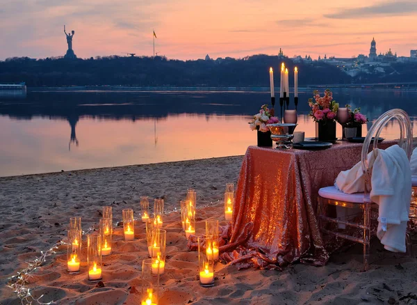 A date on the river bank, a decorated table is waiting for a couple in love. City lights in the background, evening Kyiv, Ukraine.