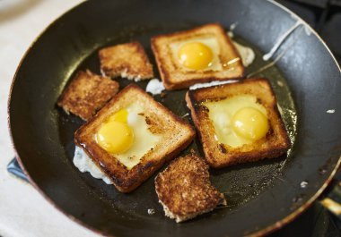 Cooking croutons with an egg inside, croutons are fried in a pan on a gas stove.