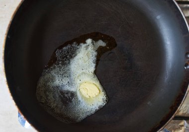 Siyah dökme demir tavada eriyen bir tereyağı..