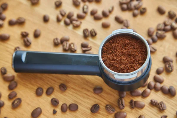 coffee machine horn, with ground coffee inside, against a background of coffee beans