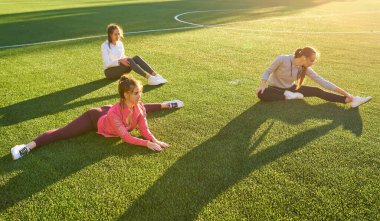 Pozitif kadın spor egzersizleri yapıyor... Üç güzel genç kadın spor güneşli bir günde parkta yapıyor grubu.